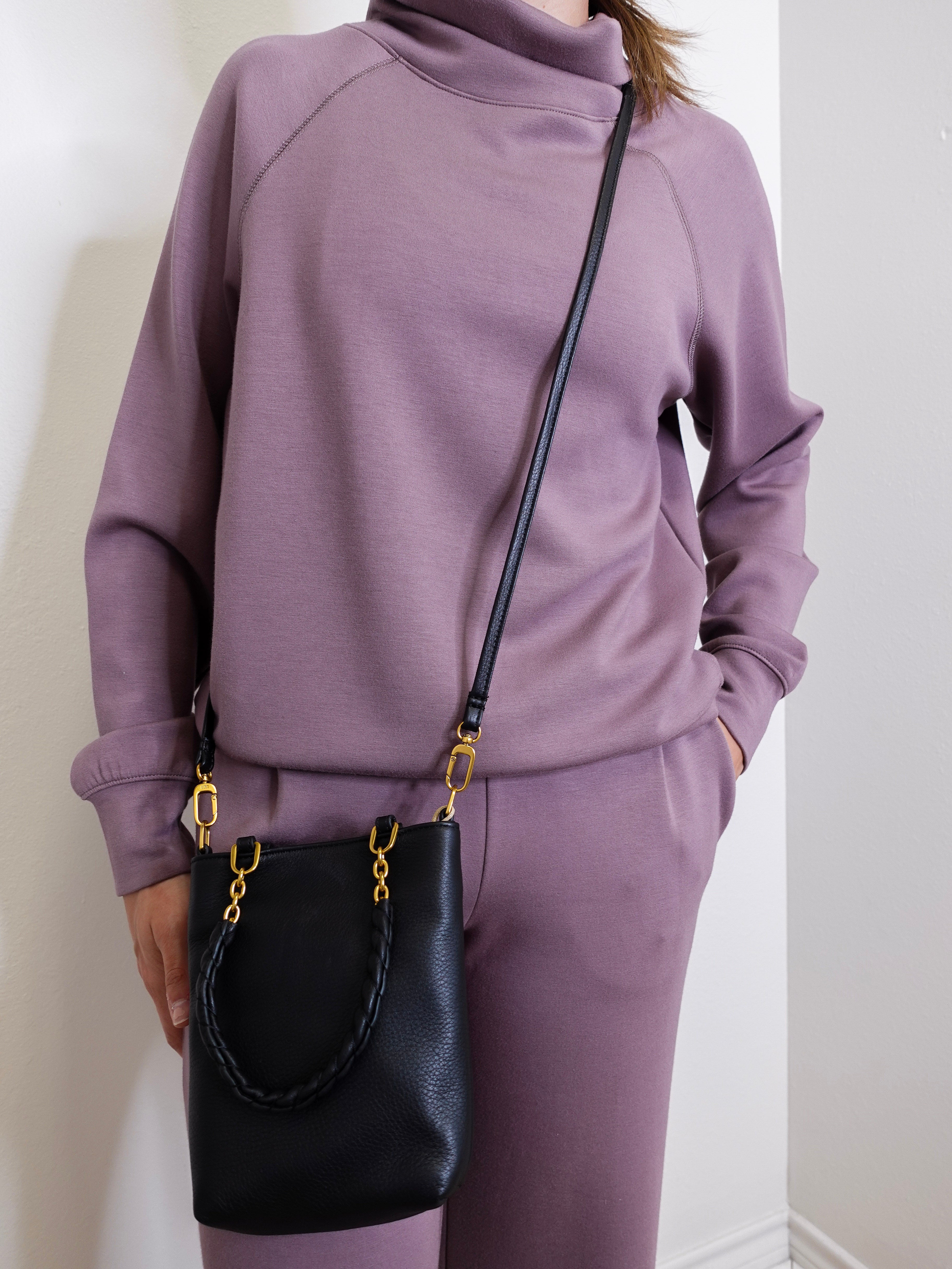 woman wearing the Black handbag with gold accents on a white background.