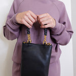 woman wearing the Black handbag with gold accents on a white background.