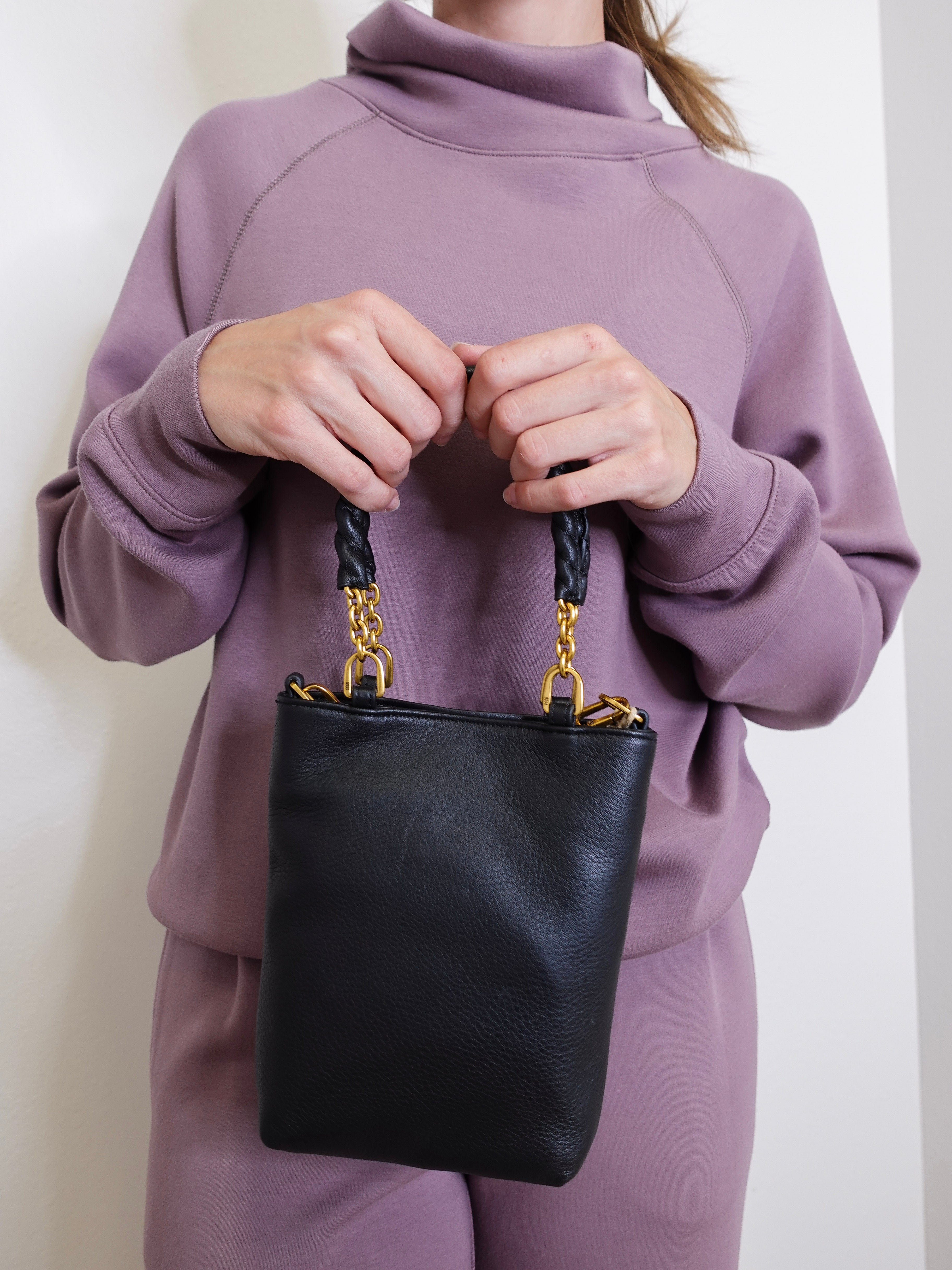 woman wearing the Black handbag with gold accents on a white background.