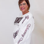 Woman wearing a white sweatshirt with brown text and graphics against a plain background
