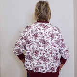 Person wearing a floral blouse with burgundy flowers on a white background