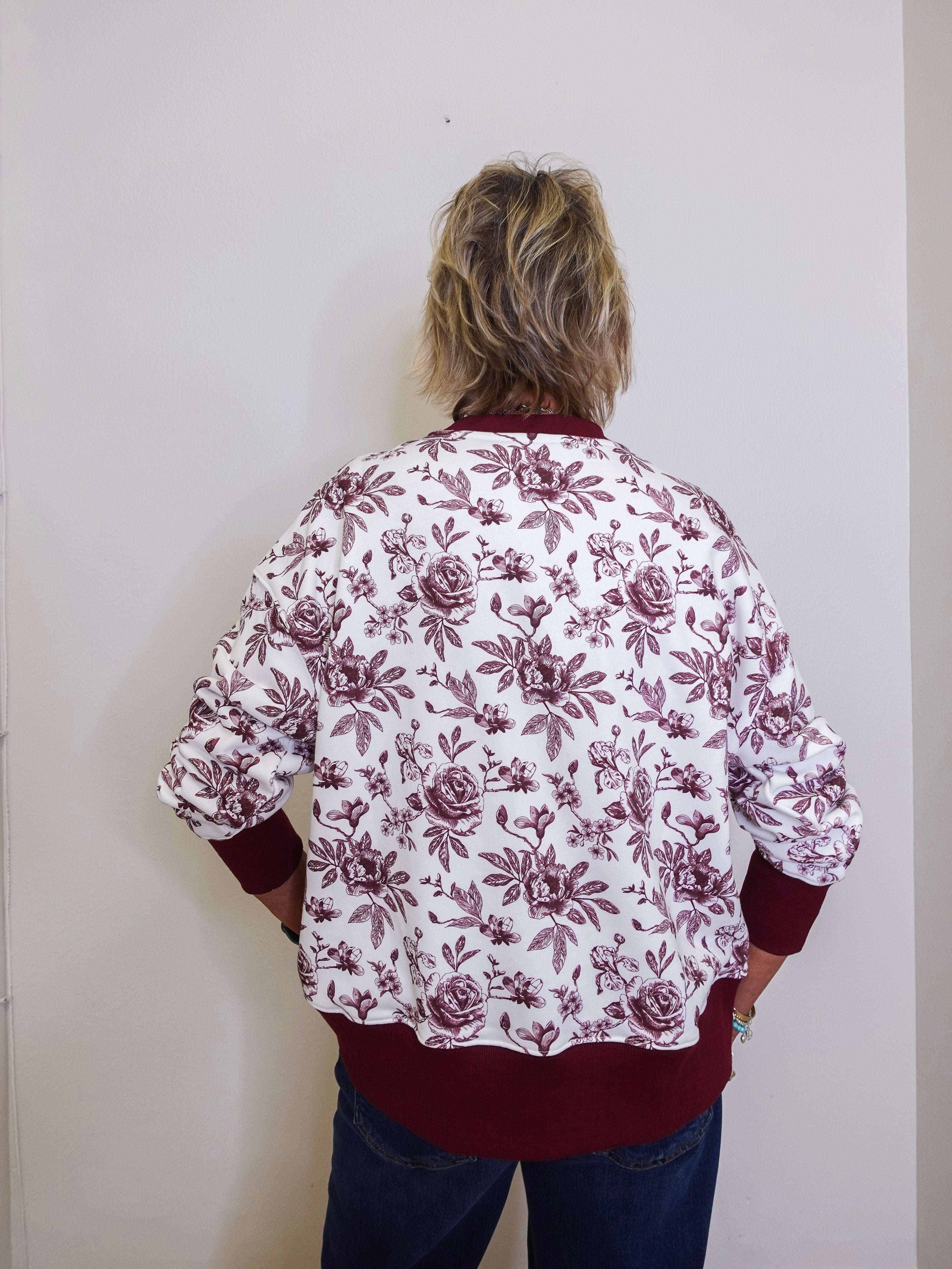Person wearing a floral blouse with burgundy flowers on a white background