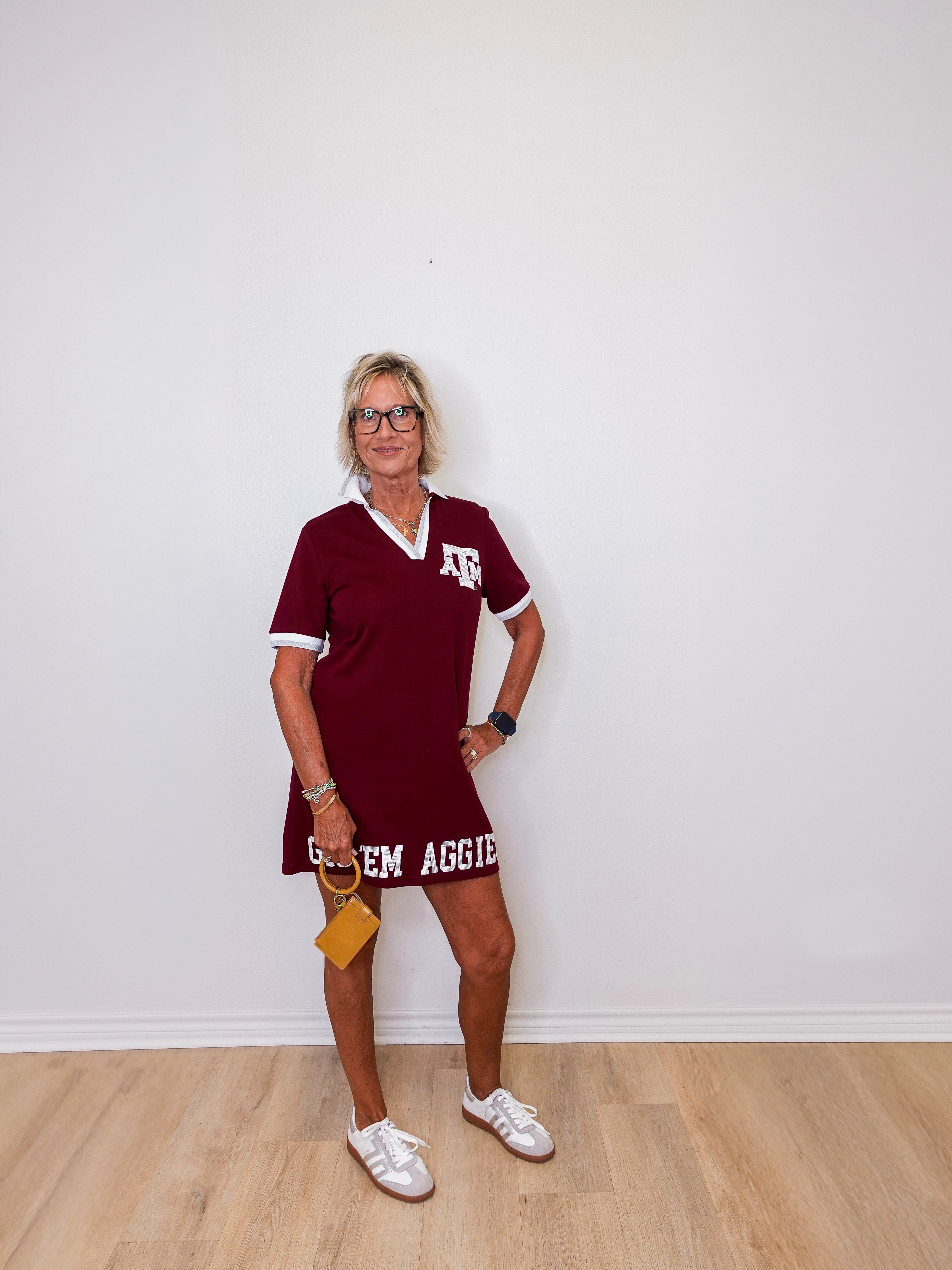 Woman wearing a maroon dress with 'Texas A&M' text against a white wall.