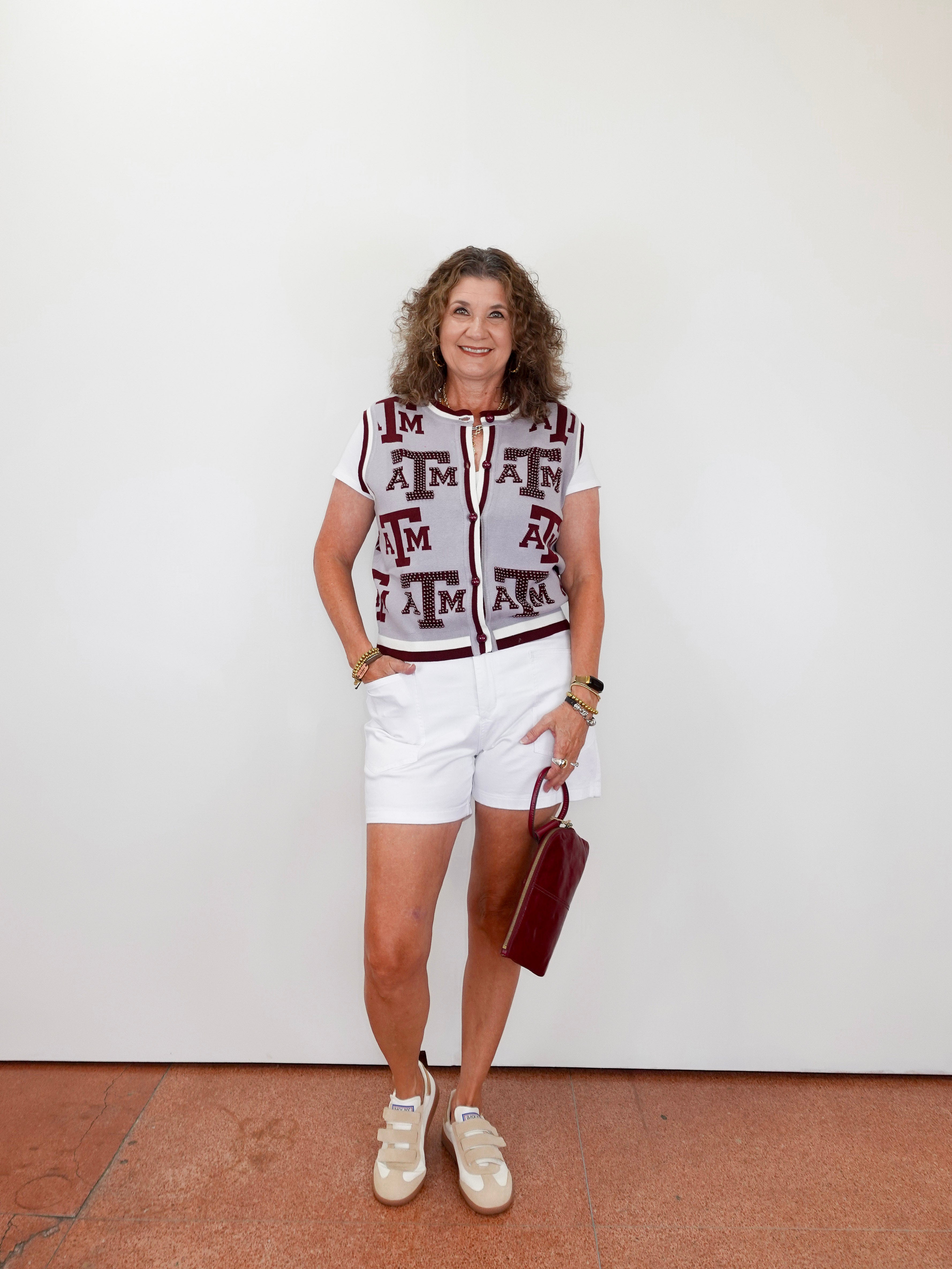 Woman wearing a patterned top and white shorts standing against a plain background