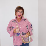 Person wearing a red and white striped shirt with patches, holding a broom and dustpan against a plain background.
