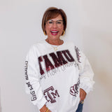 Person wearing a white sweatshirt with ' TAMU' text and graphics on a plain background
