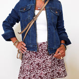 Person wearing a denim jacket, white top, and toile a&m  print skirt on a plain background