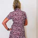 Person wearing a floral dress against a white wall