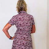 Person wearing a floral dress against a white wall