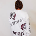 Person wearing a white long-sleeve shirt with Texas A&M University branding on a plain background