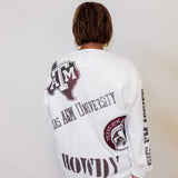 Person wearing a white long-sleeve shirt with Texas A&M University branding on a plain background
