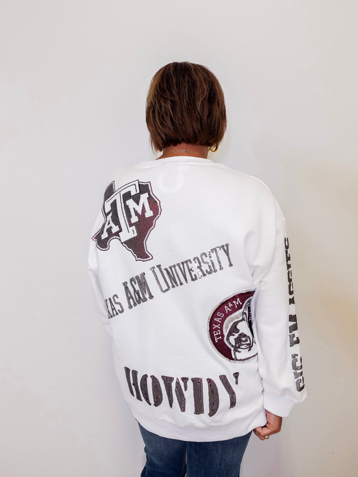 Person wearing a white long-sleeve shirt with Texas A&M University branding on a plain background