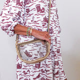 Person wearing a white dress with red patterns holding a clear handbag.