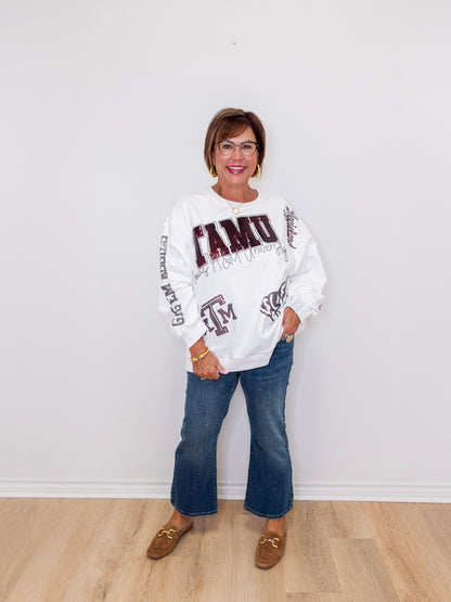 Woman wearing a white sweatshirt with text and graphics, standing against a white wall.