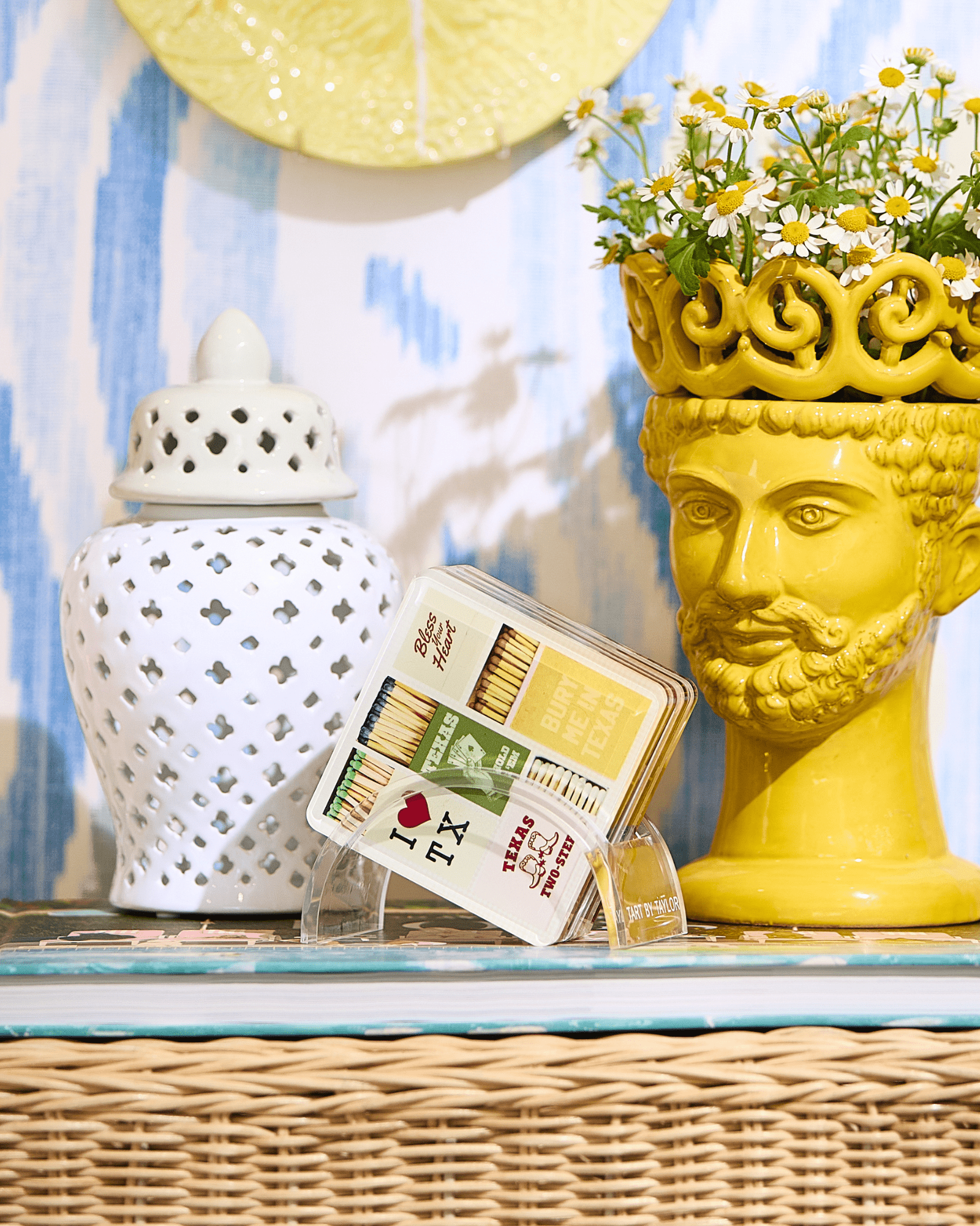 Decorative items including a yellow vase with a face, a white lantern, and a box of matches on a surface.