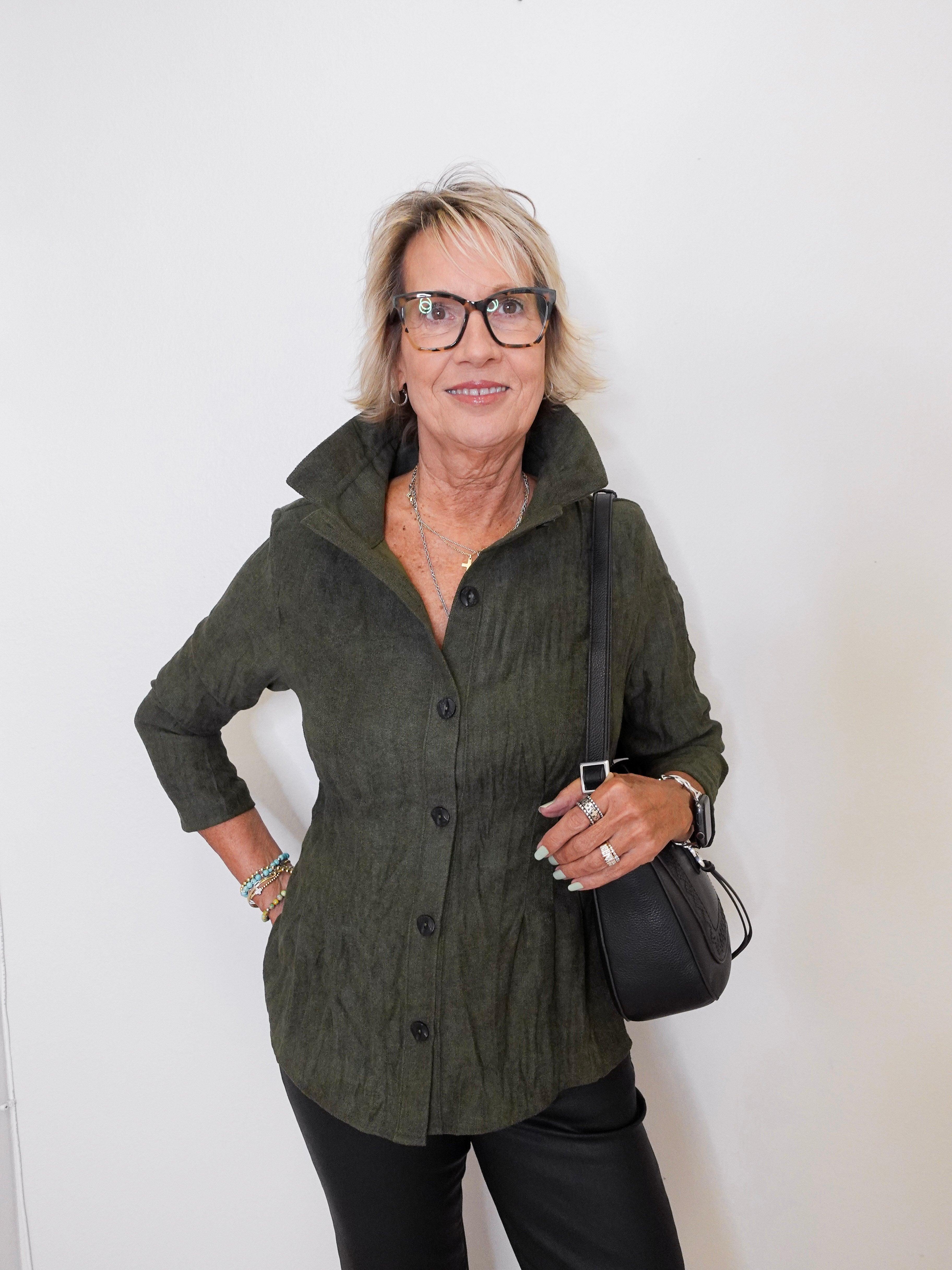 Woman wearing a green jacket and black pants against a white background