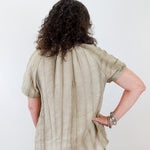 Person wearing a beige shirt and pants against a white background