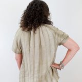 Person wearing a beige shirt and pants against a white background