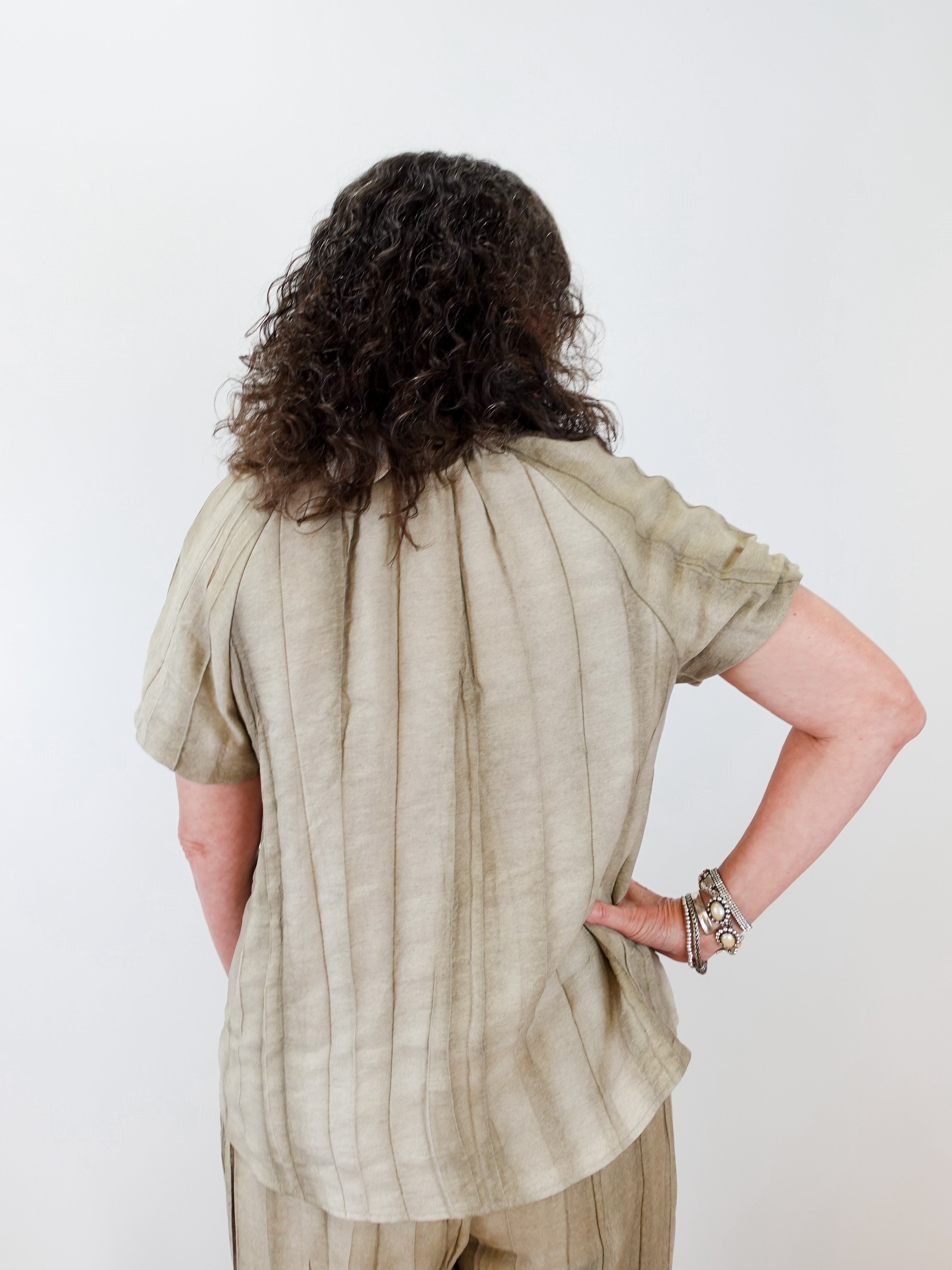 Person wearing a beige shirt and pants against a white background