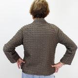 A person viewed from behind wearing a textured, ribbed brown jacket and light blue jeans against a plain white background.