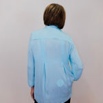 Person wearing a light blue shirt against a plain background