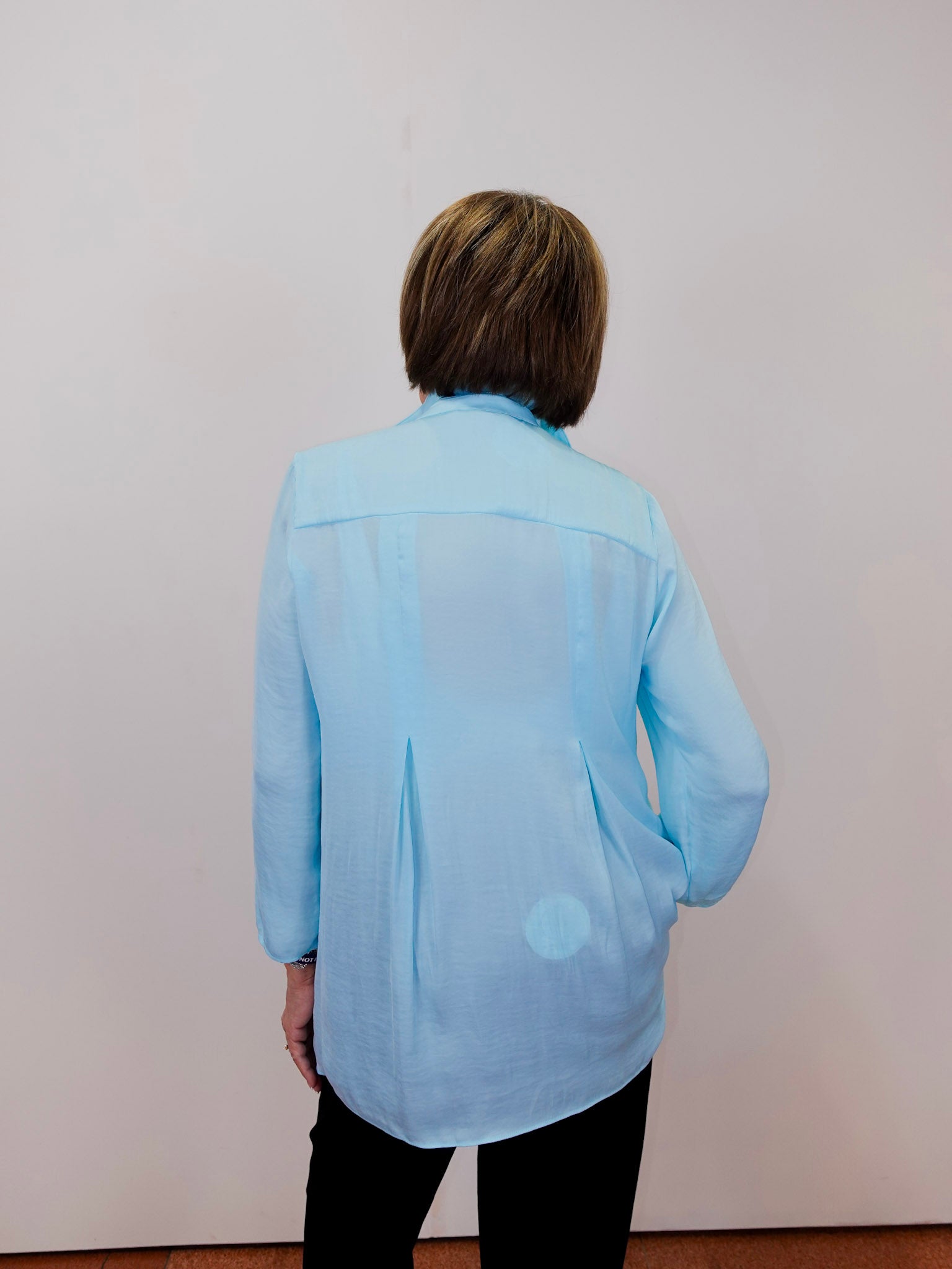 Person wearing a light blue shirt against a plain background