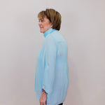 Person wearing a light blue blouse against a plain background