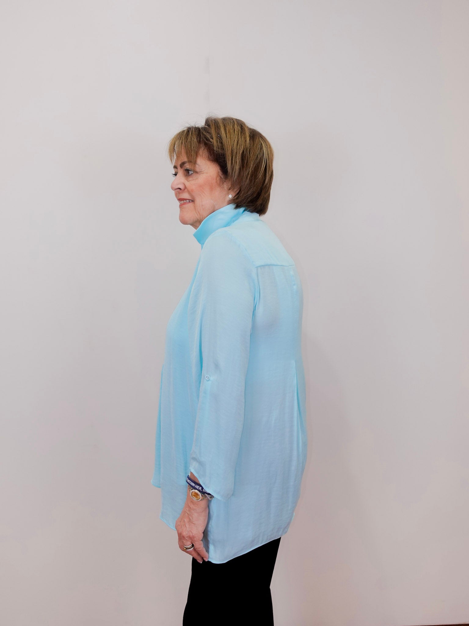 Person wearing a light blue blouse against a plain background