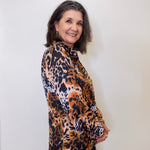 Woman wearing a leopard print blouse against a white wall