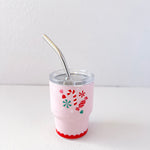 Pink tumbler with festive design and metal straw on a white background
