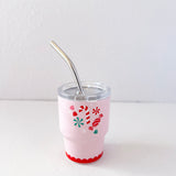 Pink tumbler with festive design and metal straw on a white background