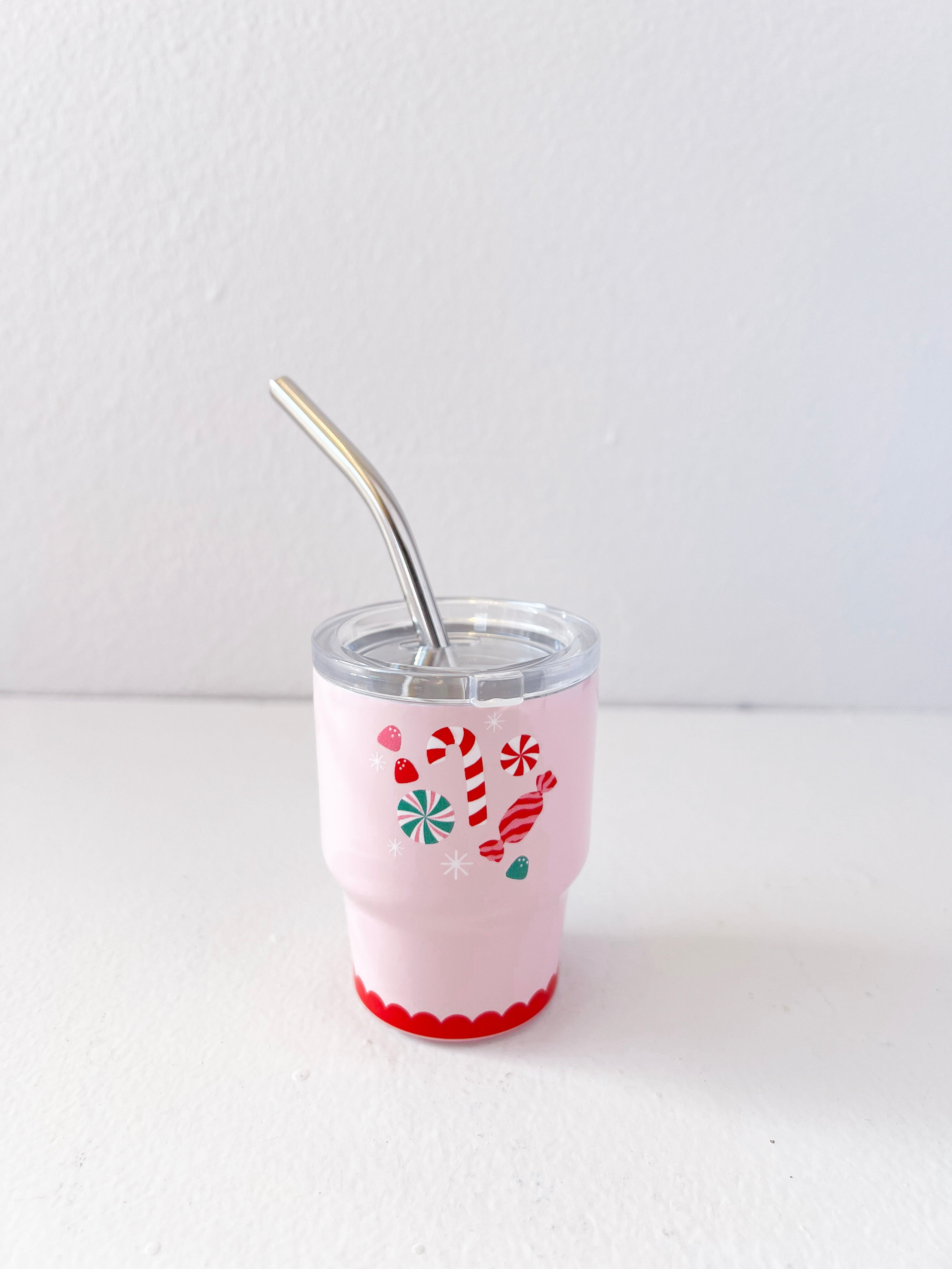Pink tumbler with festive design and metal straw on a white background
