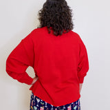 Person wearing a red sweatshirt and colorful shorts against a white background
