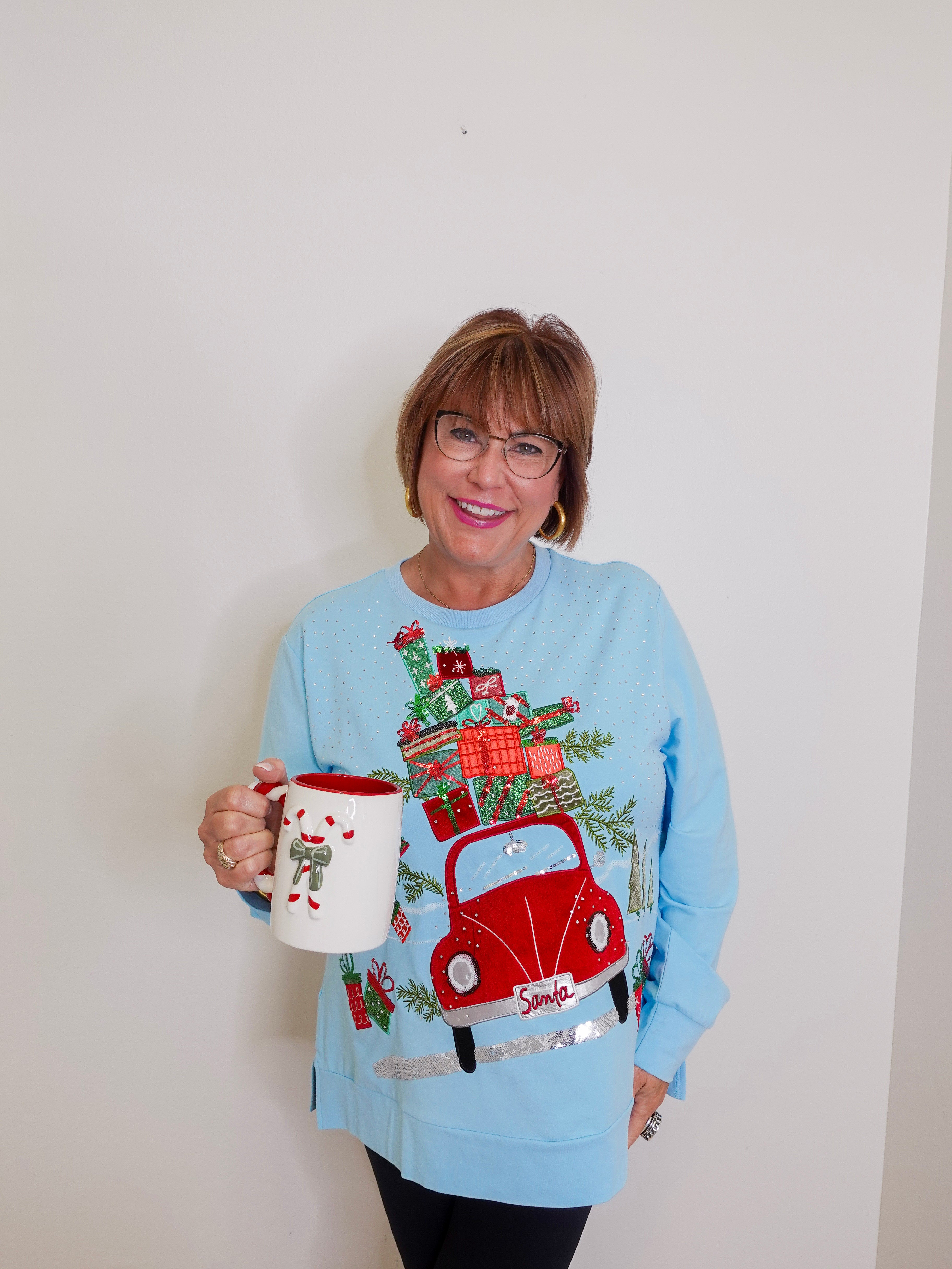 woman wearing a grandmas house knit top in blue against a white background. 