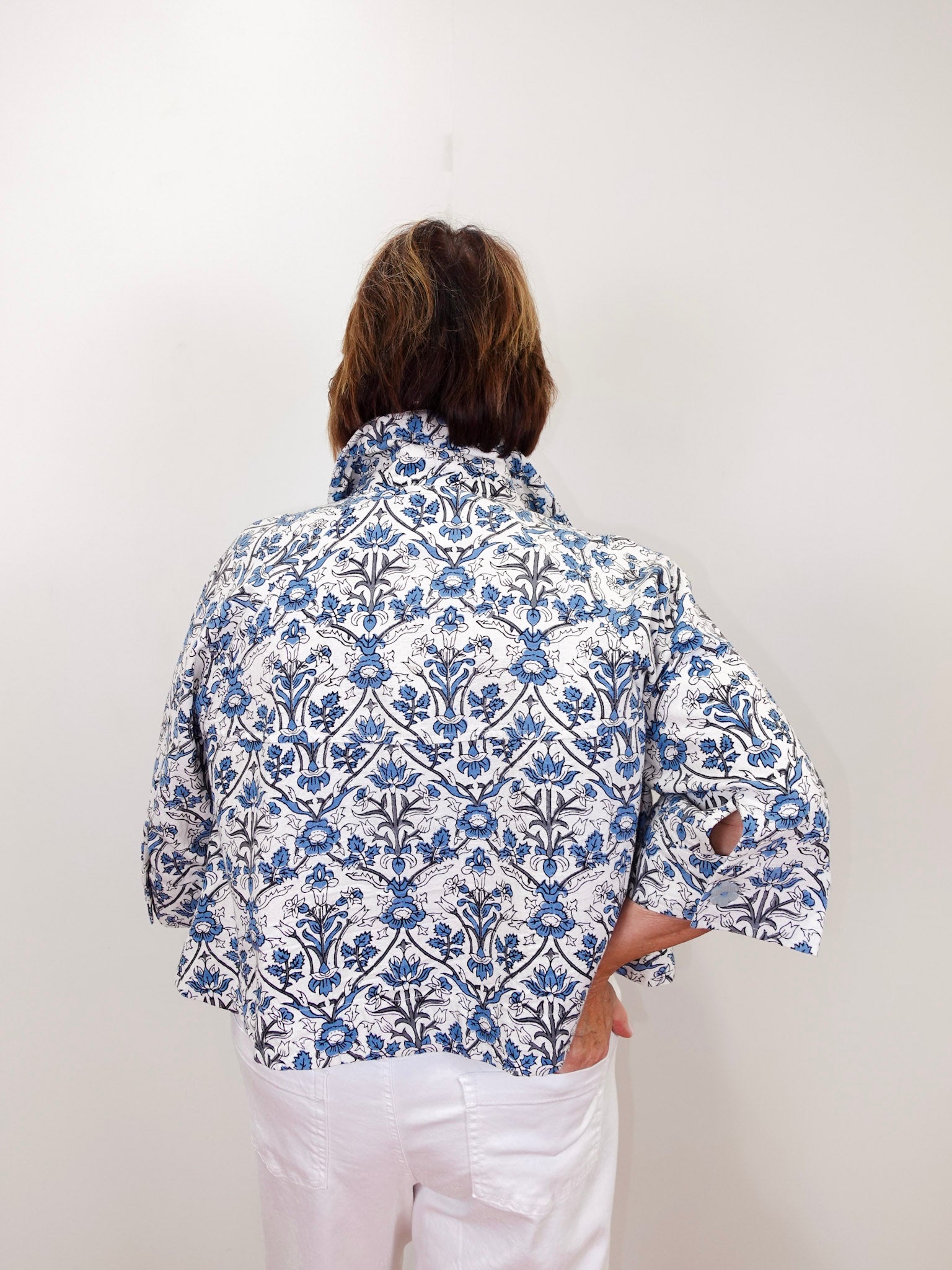Person wearing a blue and white patterned shirt against a white background
