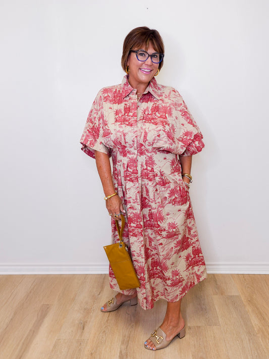 Woman wearing a red and white floral dress holding a yellow handbag against a white wall.