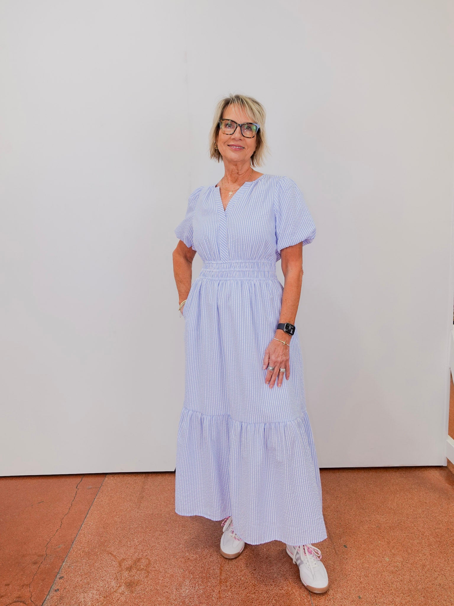 Woman wearing a light blue dress standing against a white wall.