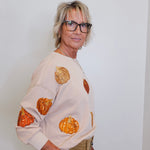 woman wearing a pumpkin sequins sweatshirt against a white background 