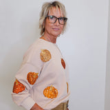 woman wearing a pumpkin sequins sweatshirt against a white background 