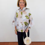 Woman wearing a floral blouse and holding a handbag against a white background