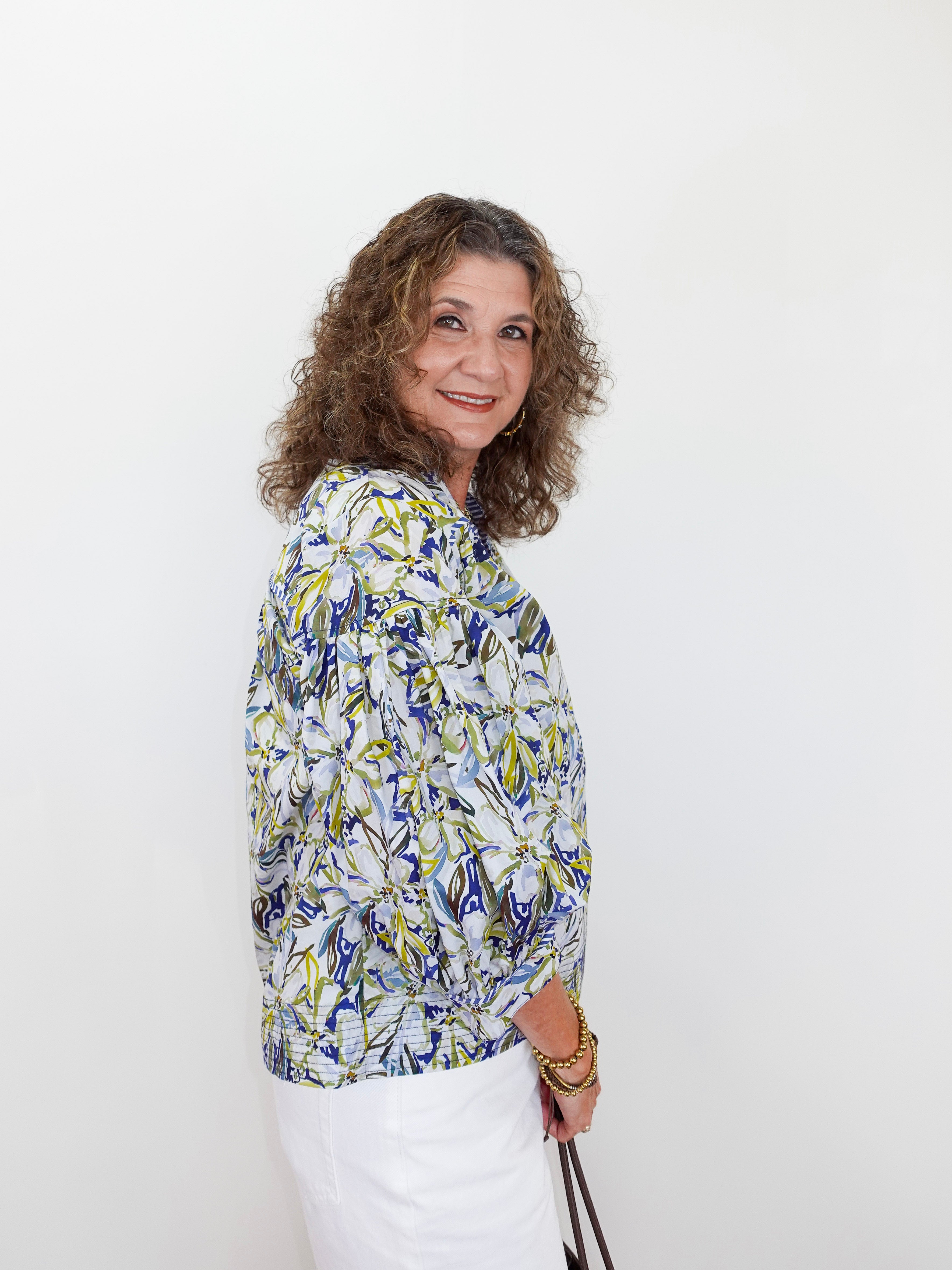 Woman wearing a patterned blouse against a white background