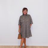 Woman wearing a patterned dress with a plain white wall background