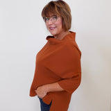 Woman wearing a brown poncho against a white background