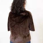 Person wearing a brown fur jacket on a white background