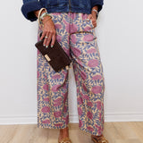 Person wearing a denim jacket, patterned pants, and brown loafers against a white wall.