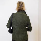 Person wearing a green textured jacket with a black bag on a white background