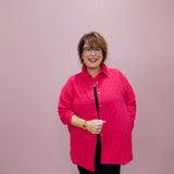 Woman wearing a pink quilted jacket against a plain background
