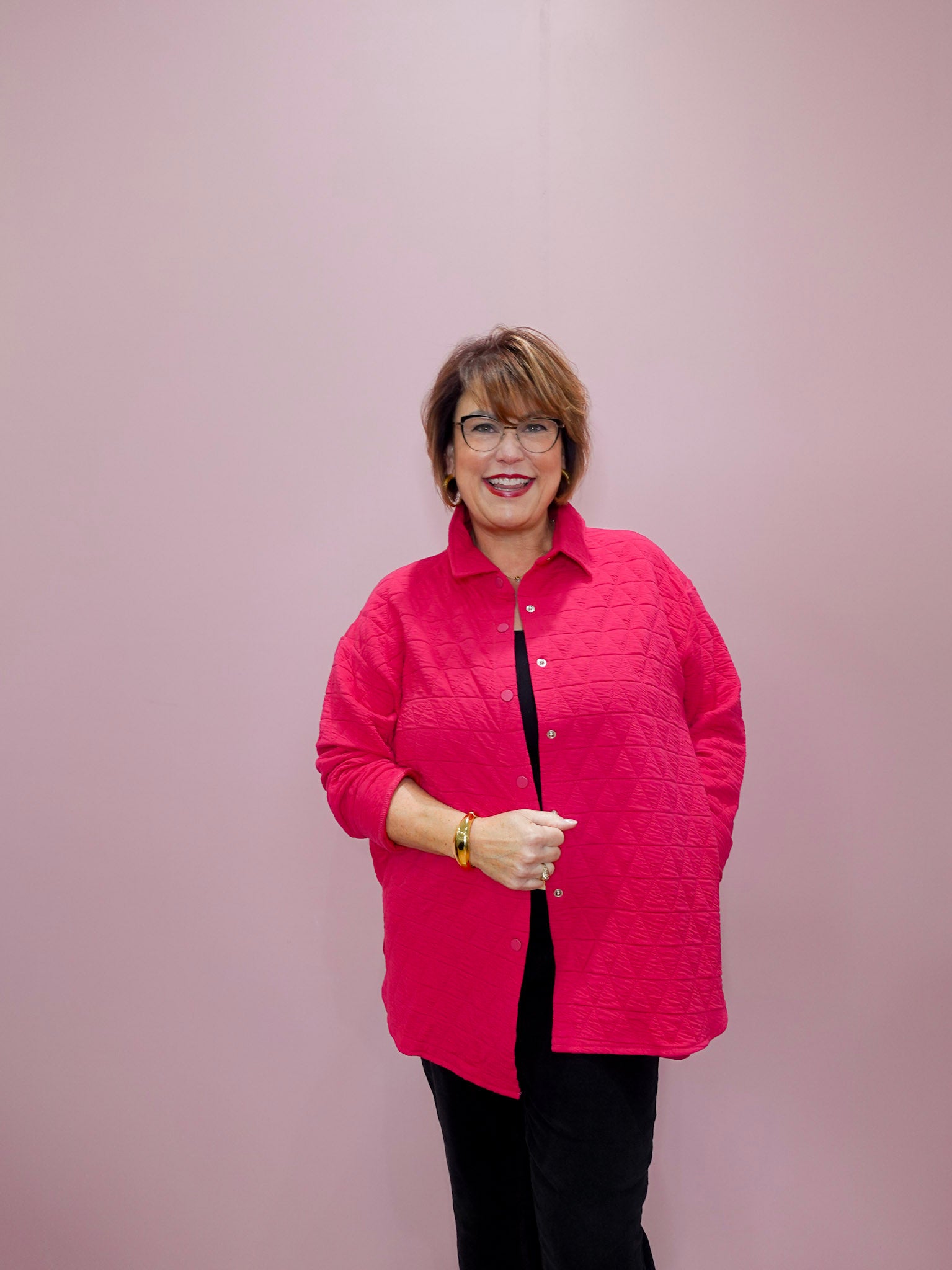 Woman wearing a pink quilted jacket against a plain background