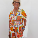 Woman wearing a colorful patterned outfit against a white background