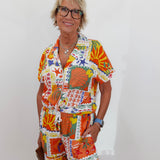 Woman wearing a colorful patterned outfit against a white background